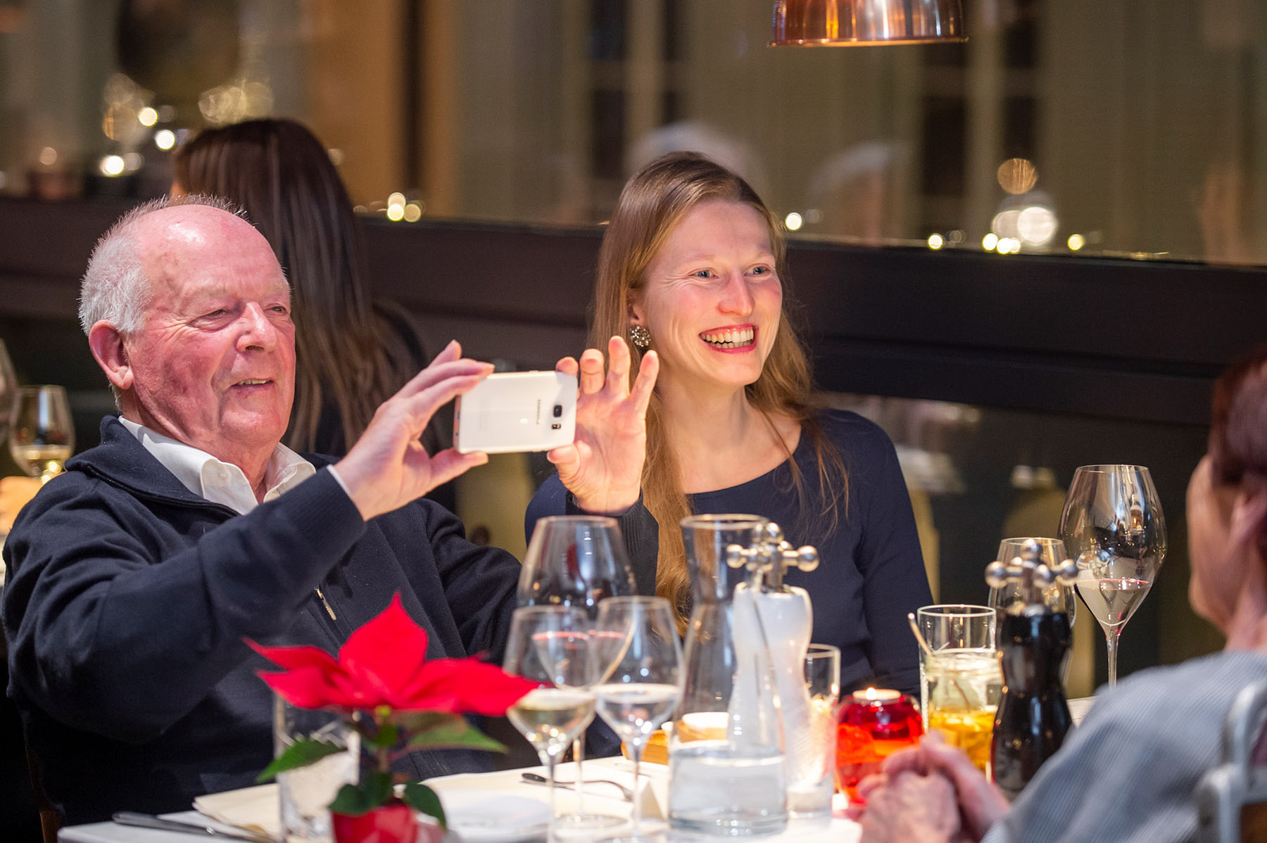 Senior fotografiert Tischpartner beim Tertianum Generationen Dinner