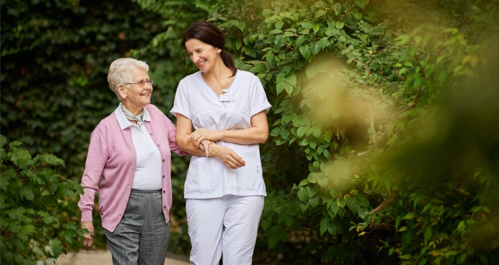 Arbeiten bei der Tertianum Premium Group - Mitarbeiterin in der Pflege begleitet ältere Dame beim Spaziergang