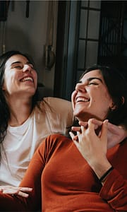 Zwei Frauen sitzen auf Sofa und genießen, dank RAS Concierge Service, eine unbekümmerte Zeit.