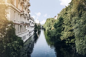 Historisches Gebäude an Kanal mit Bäumen - RAS After Sales Services