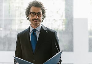 lächelnder Mitarbeiter mit Kladde - RAS Office Management bedeutet souveräne Präsenz