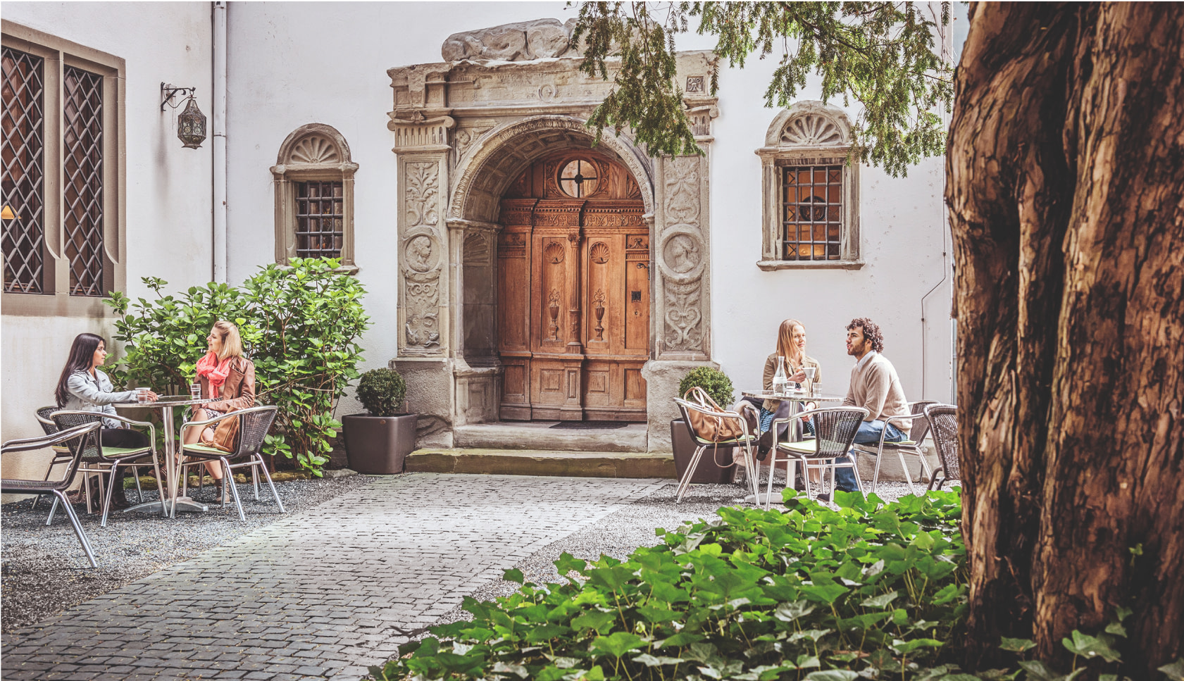 Menschen sitzen an Tischen vor dem Rosengartenmuseum in Konstanz