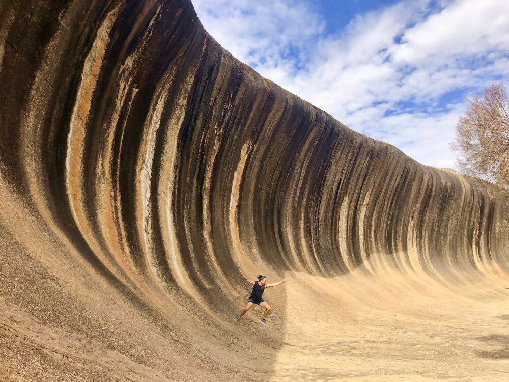 Mann posiert als Surfer am Wave Rock in Hyden, Australien.