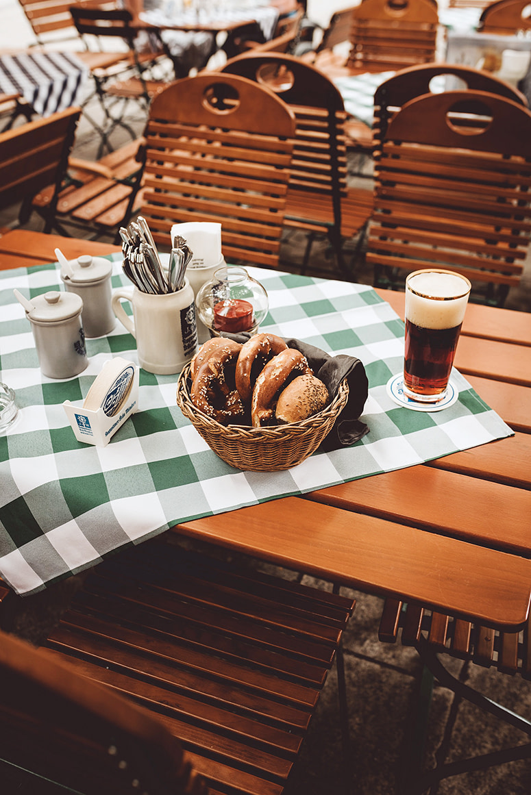 Leben kennt kein Alter - München Reiseführer für Senioren: gedeckter Tisch im Biergarten mit Brezeln und einem Bierglas Münchner Dunkles