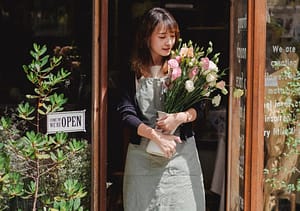 Frau mit Blumen verlässt Geschäft - RAS Reception Services beherrscht die Welt der Vermittlungen