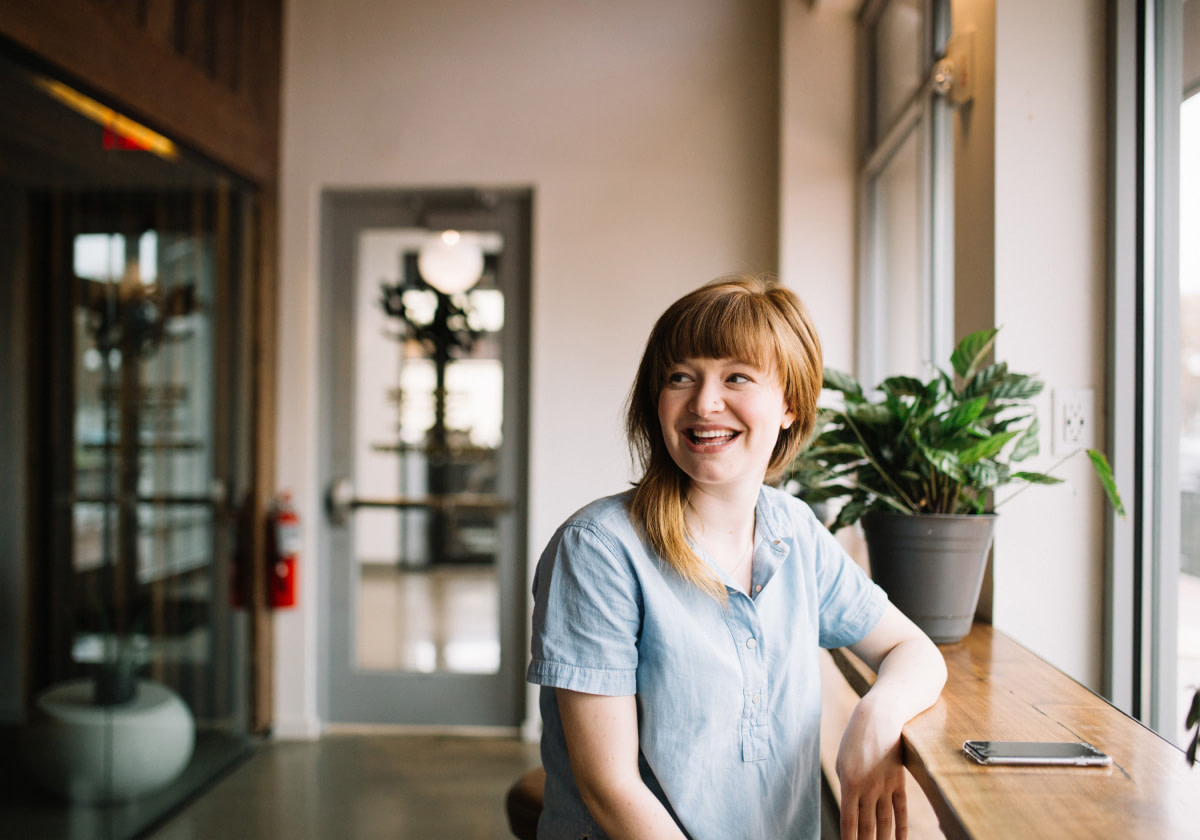 lächelnde Frau an Tisch - RAS Office Management steht für flexible Hilfsbereitschaft