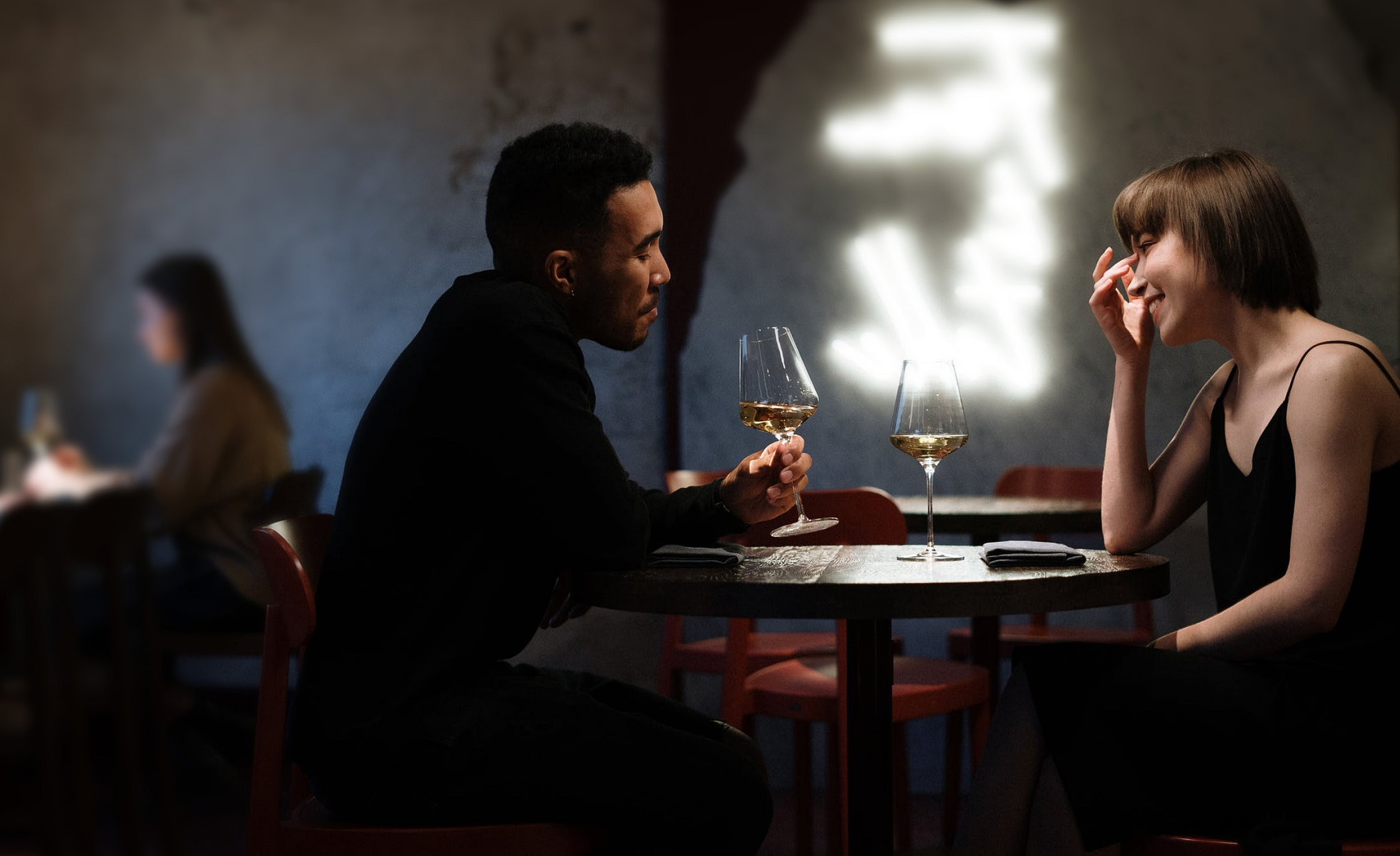 Mann und Frau sitzen an Restauranttisch und trinken ein Glas Wein. RAS Customer Services erleichtert Ihren Alltag und reserviert z.B. kurzfristig einen Tisch in Ihrem Lieblingsrestaurant.