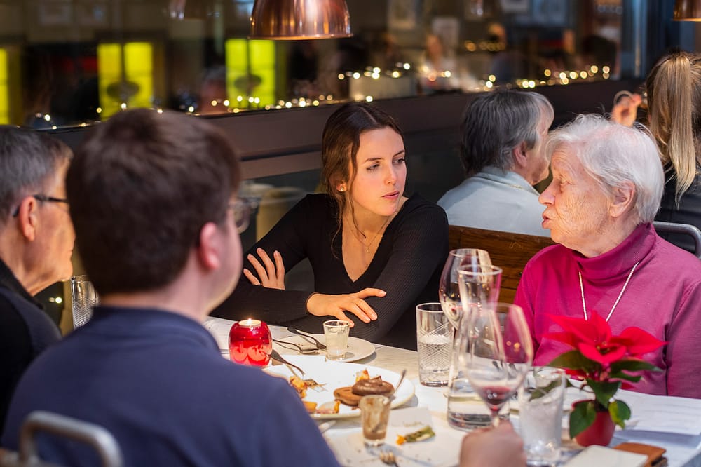 Seniorin spricht mit Sitznachbarin bei Tertianum Generationen Dinner