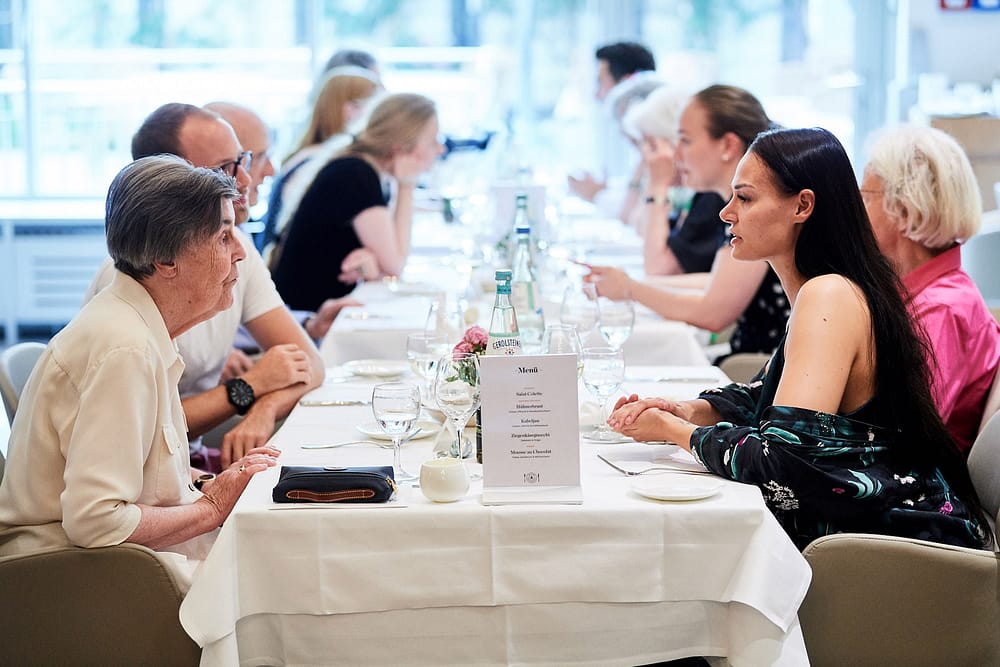 Teilnehmer des Generationen Dinners sitzen an gedeckter Tafel