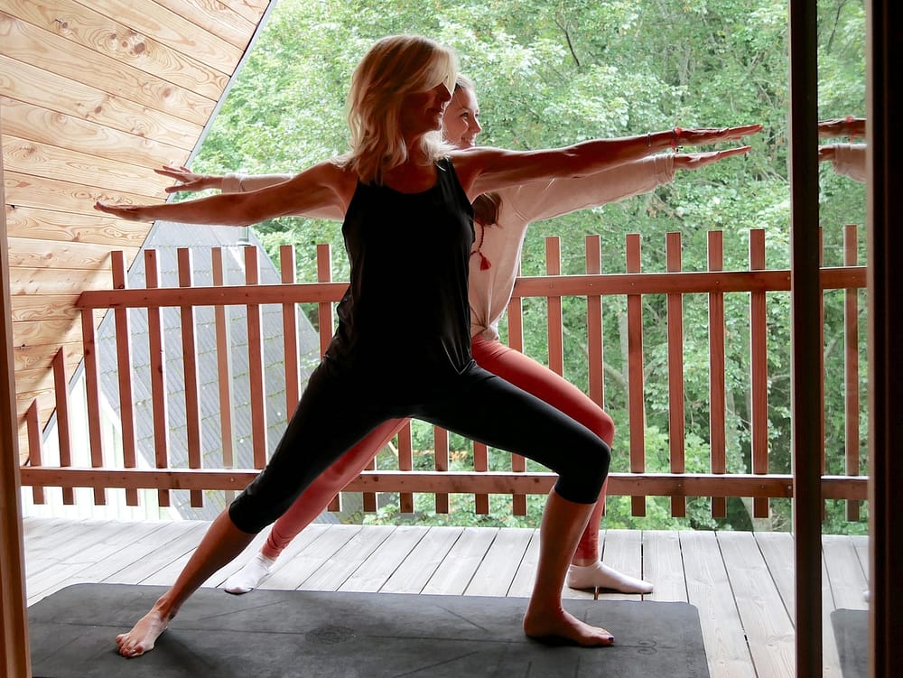 Zwei Frauen machen Yoga auf einem Balkon