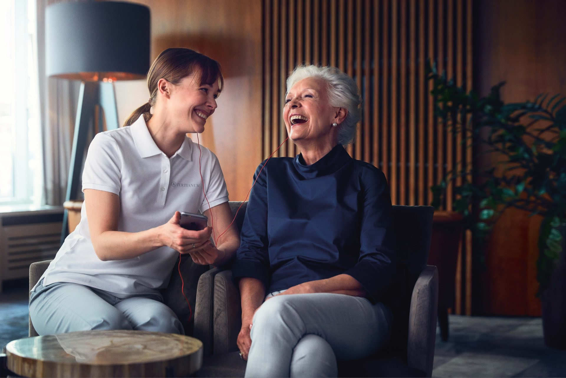 Seniorin mit einer Pflegerin lachend