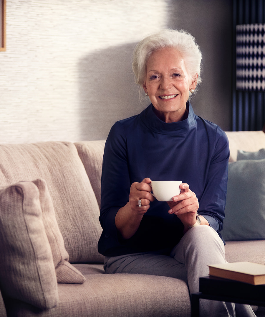 Seniorin in ihrer Wohnung mit einer Tasse Tee