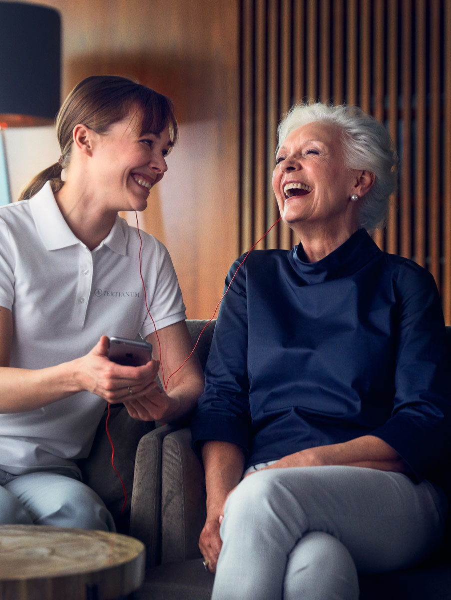 Eine ältere Dame lachend im Gespräch mit einer Pflegekraft