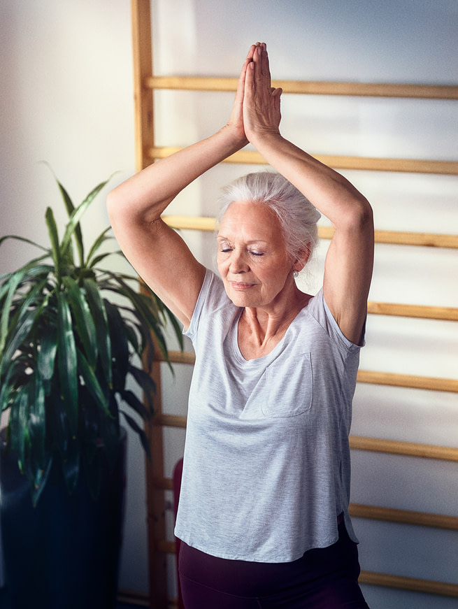 Eine ältere Dame, die eine Yogapose macht im Seniorenhaus Tertianum