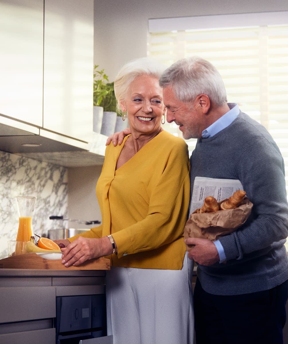 Zwei glückliche Senioren in der Küche ihrer Seniorenwohnung in der Tertianum Residenz