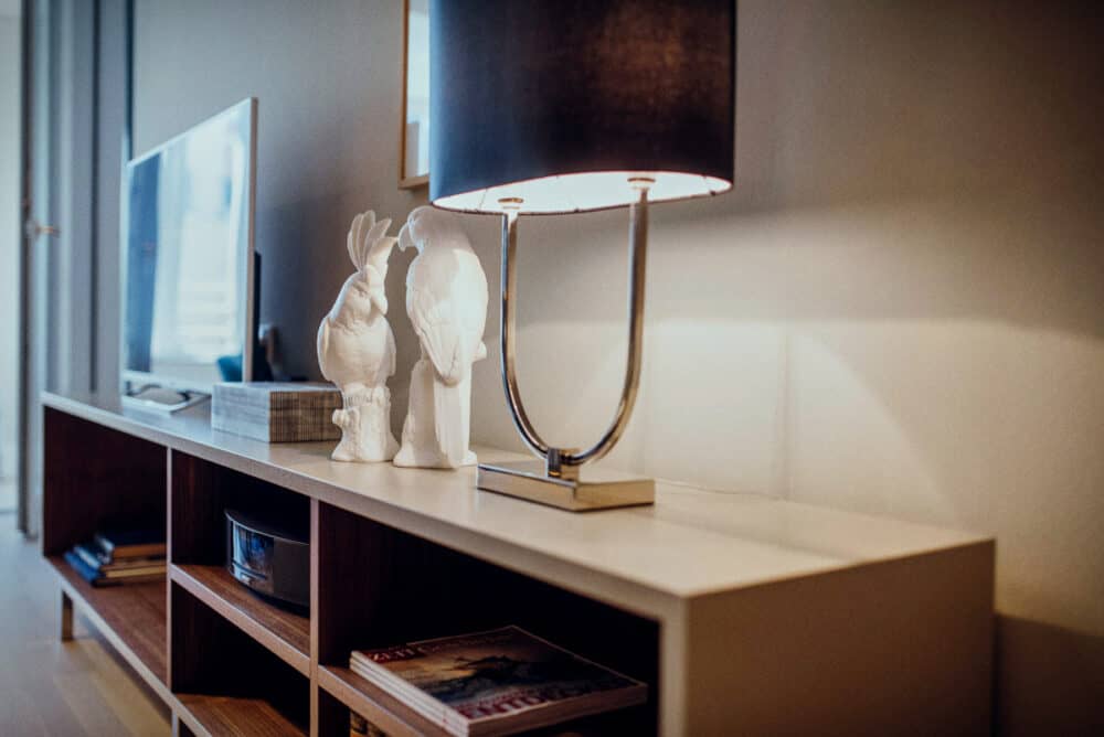 Inneneinrichtung der Seniorenresidenz Tertianum. TV-Sideboard aus braunem Holz mit Stehlampe