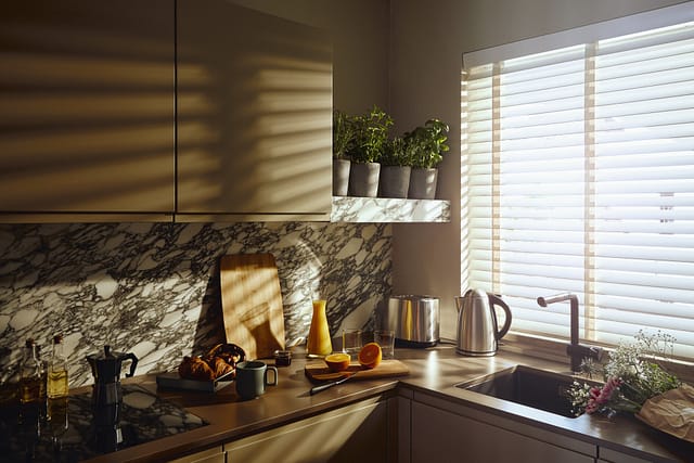 Die Küche einer Gästewohnung mit Croissants, Orangen und Kaffee und großem Fenster in der Tertianum Senioreneinrichtung.