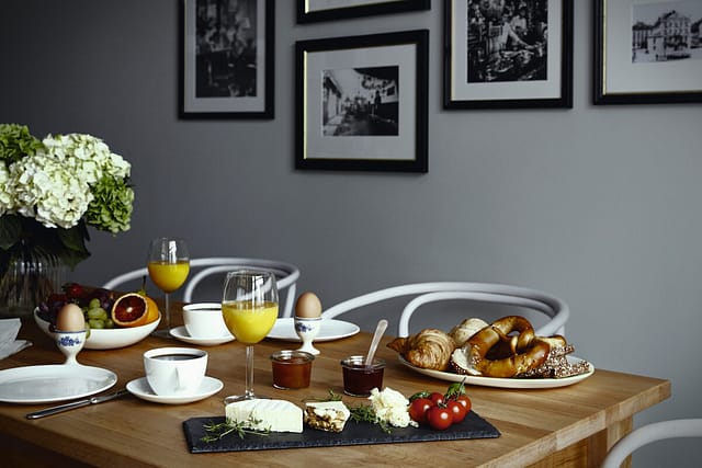 Ein reichlich gedeckter Frühstückstisch mit Orangensaft, Käse, Ei, Obst, Gebäck in einer Gästewohnung im Seniorenhaus Tertianum