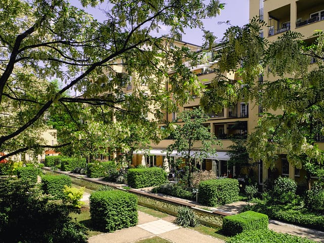 Ein grüner Garten und die gelbe Fassade der Tertianum Senioreneinrichtung.