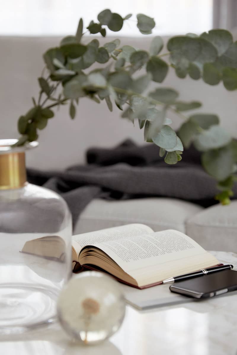 Ein aufgeklapptes Buch und eine Blumenvase auf dem Couchtisch einer Seniorenwohnung im Tertianum