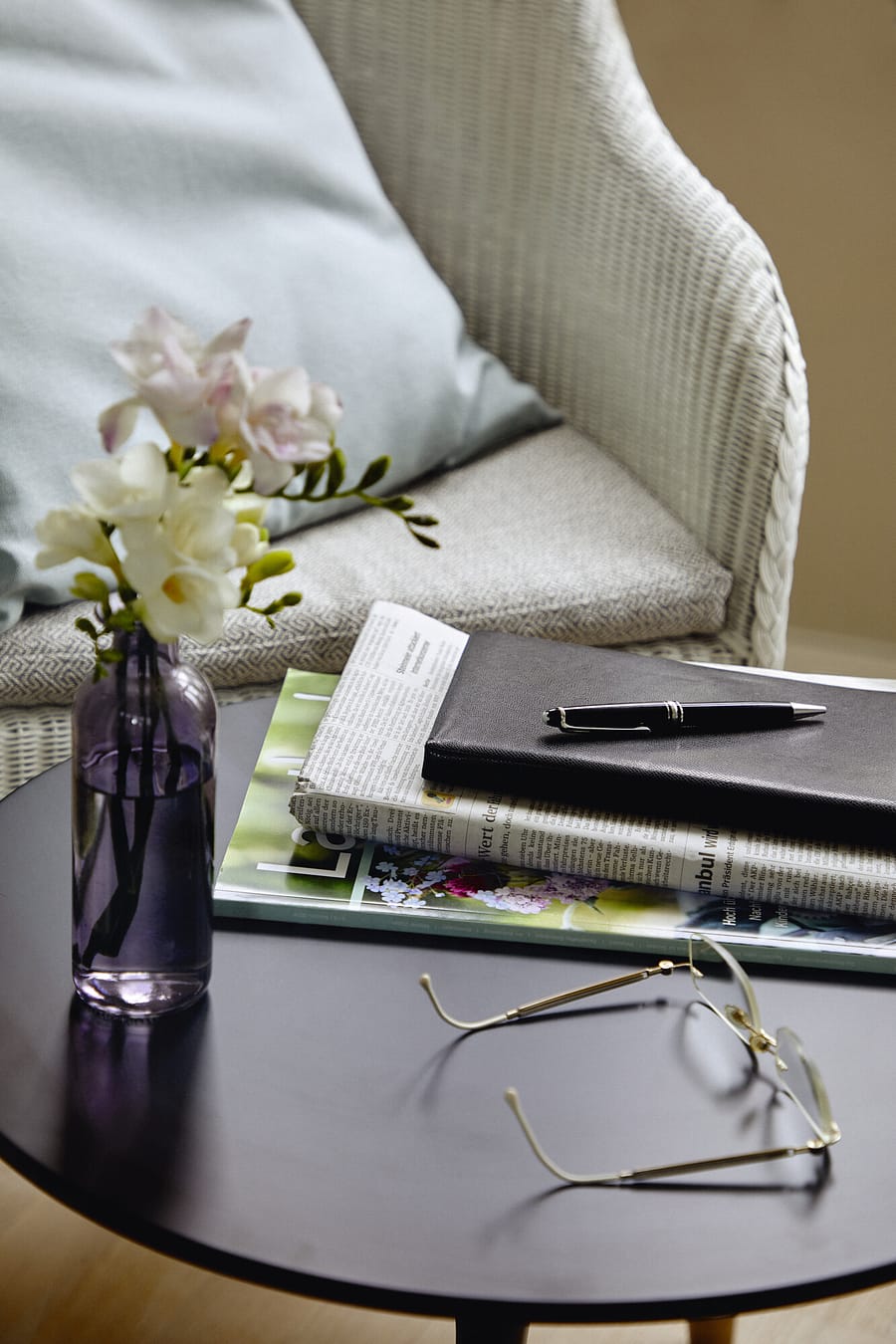 Ein Sessel und ein Tisch, auf dem Blumen, eine Brille und etwas zu lesen liegt, in einer Gästewohnung im Seniorenhaus Tertianum.