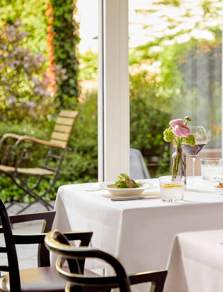 Ein gedeckter Tisch mit einer Blumenvase im Wintergarten der Tertianum Premium Residenz