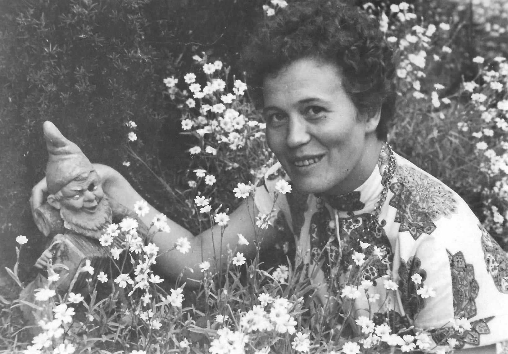 Historisches Foto von Inge Karsch von 1956 inmitten von Blumen mit einem Gartenzwerg (aus dem Archiv der Galerie Nierendorf)