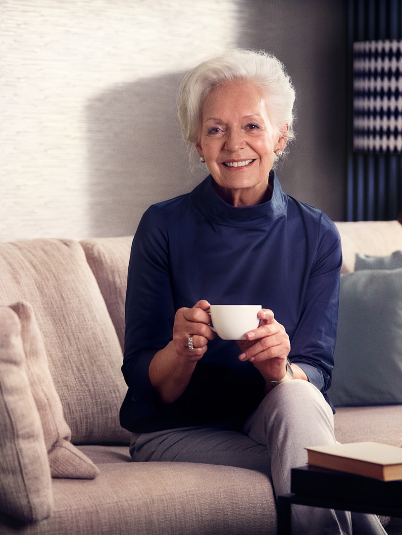 Eine lächelnde Seniorin beim Kaffee trinken in ihrer Tertianum Residenzwohnung