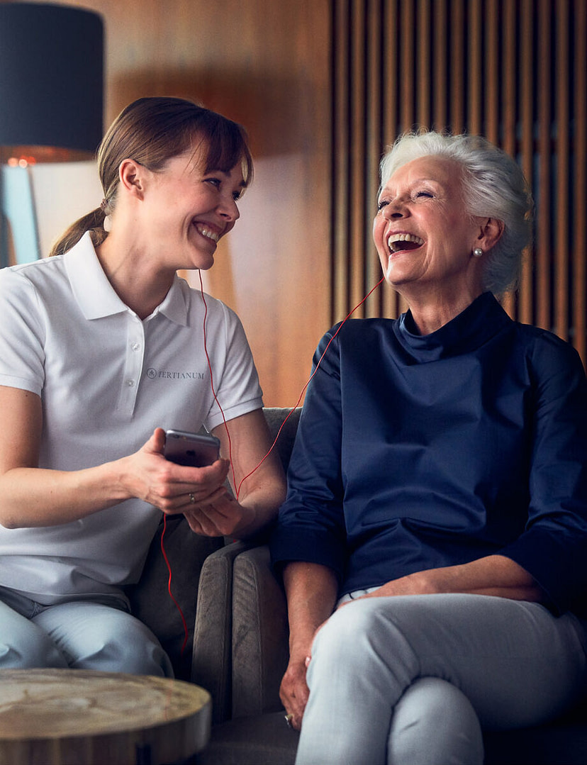 Lachende Seniorin mit Pflegehelferin im Altersruhesitz Tertianum