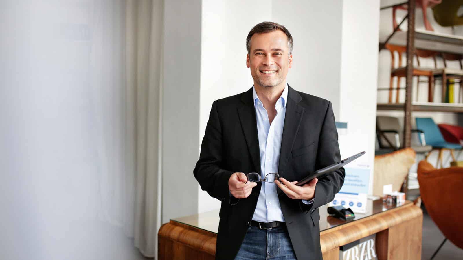 Möbelgeschäft-Inhaber hat Brille und Tablet in der Hand