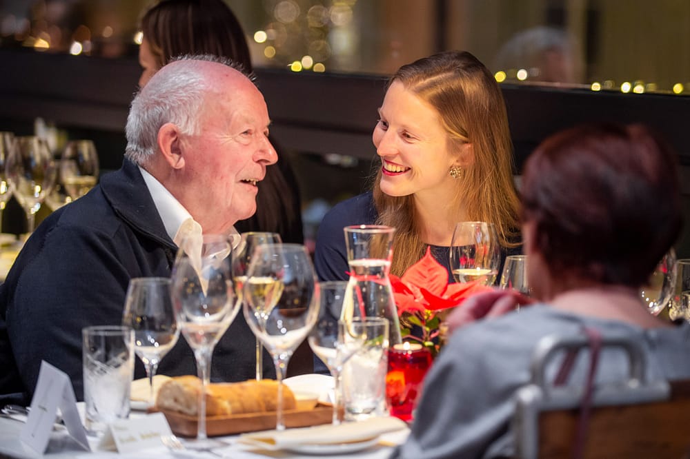 Generationen Dinner: Studentin unterhält sich angeregt mit älterem Herrn