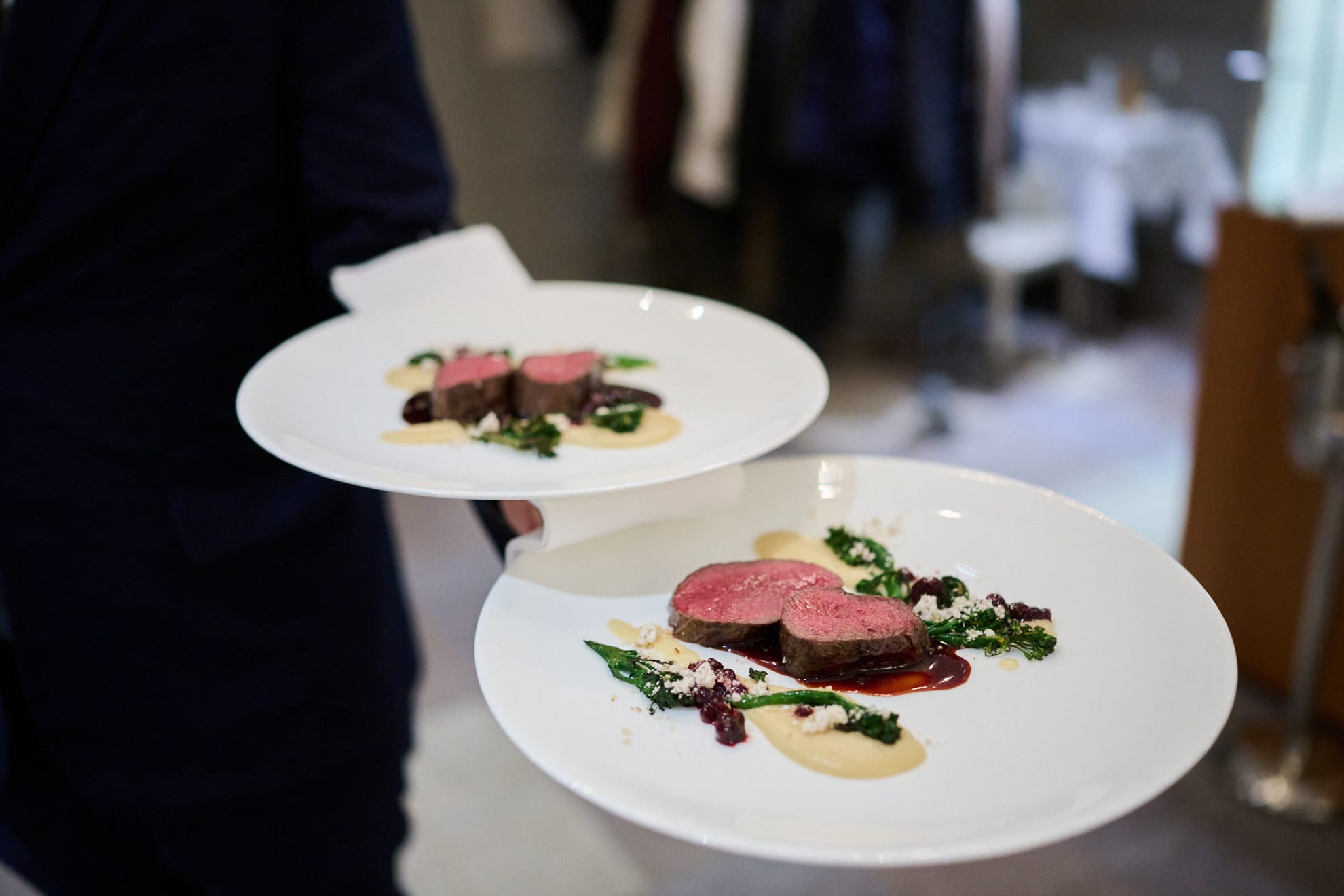 Person serviert zwei Teller mit arrangierten Fleischgerichten beim Tertianum Generationen Dinner