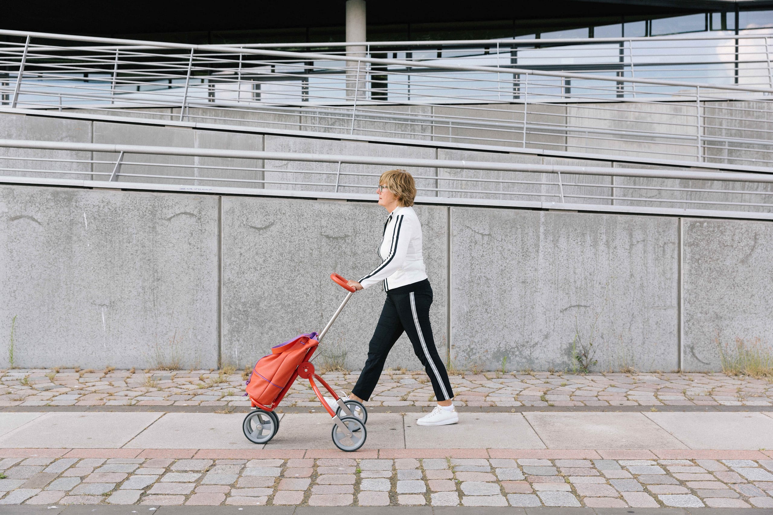 Sportliche Dame schiebt roten Golf Caddy