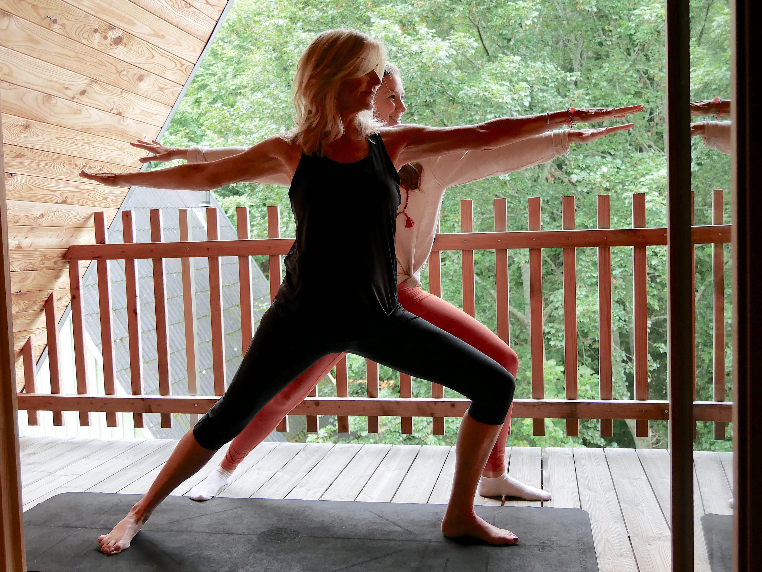 Zwei Frauen machen Yoga auf einem Balkon